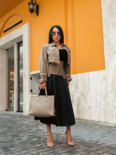 Woman in stylish attire poses confidently outdoors.