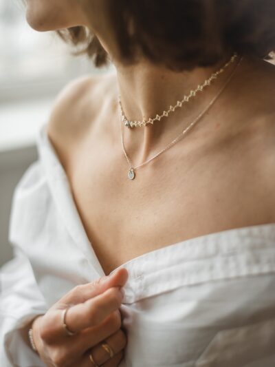 woman in white off shoulder shirt wearing silver necklace