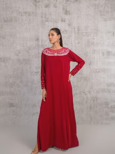 A woman in a long red dress standing in front of a wall