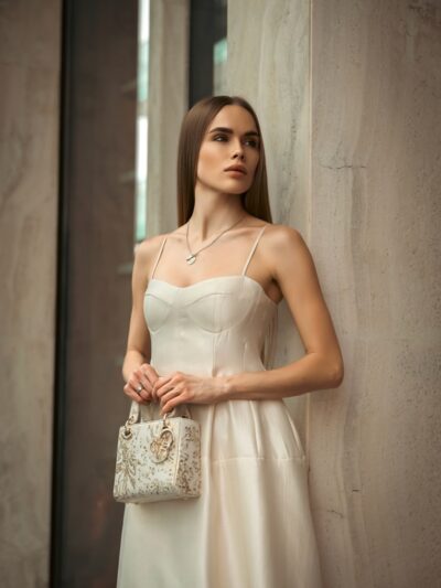 Elegant woman in a white dress holding a purse.