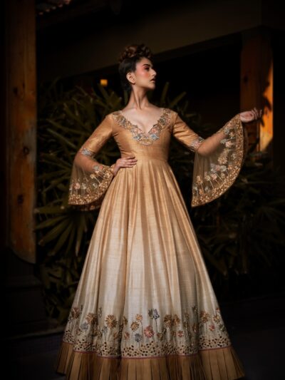 Woman in elegant golden gown with embroidered sleeves.