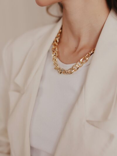 A woman wearing a white jacket and a gold necklace