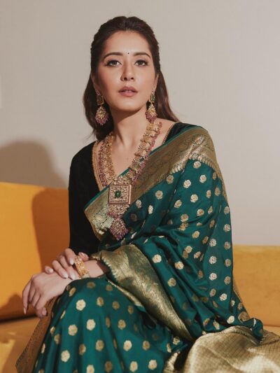 A woman sitting on a couch wearing a green and gold sari