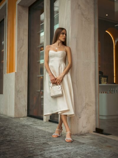 Woman in elegant dress poses outdoors.