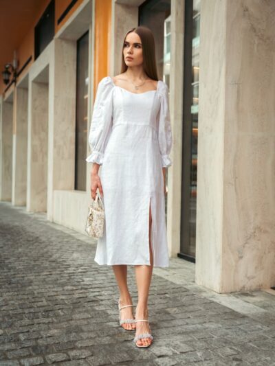 Woman walks confidently in a stylish white dress.